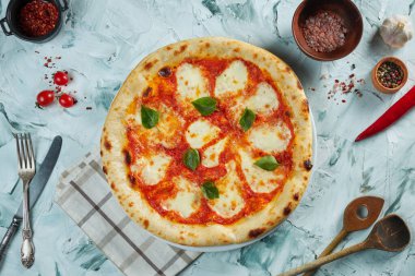 Domatesli taze kızarmış pizza ve mozzarella. Gri arka planda pizza Margherita. İçinde malzemeler ve mutfak aletleri olan bir kompozisyon.
