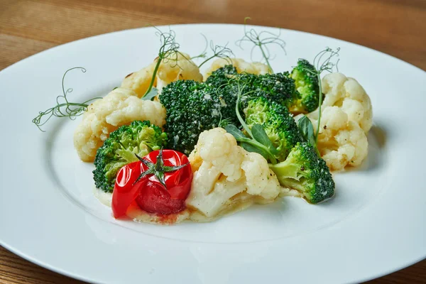 Diet and veggie snack - steamed vegetables (broccoli, cauliflower and cherry tomatoes) in a white plate on a wooden background