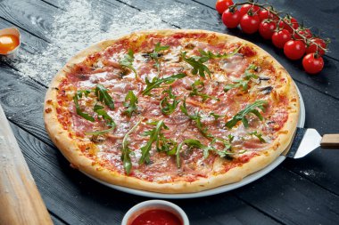 Kırmızı soslu fırında pizza ve siyah ahşap arka planda eritilmiş peynir içerikli kompozisyon. Üst görünüm
