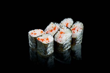 Geleneksel Japon maki suşisi, kafa derisi ve tobico havyarla birlikte siyah arka planda yansıtılır. Menü için fotoğraf. Kapat.