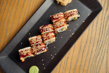 Geleneksel Japon suşi rulosu, siyah tabakta yılan balığı, salatalık, krem peynir ve somon. Kapatın. Menü için yemek fotoğrafı