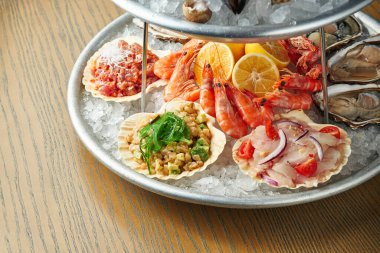 Lezzetli tabağı buzlu deniz ürünleriyle kapatın. Deniz tarağı, deniz levreği ve deniz kabuğu, karides ve istiridye. Sağlıklı Antipasti. Ahşap arka plan. Seçici odak