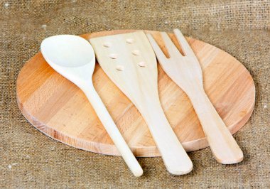 Bir çatal, kaşık ve kürek kemiği ışık tahtadan yapılır. Pişirme kavramı. Gıda karıştırma için araçları yuvarlak bir gemide yalan. Yatay studio resim.