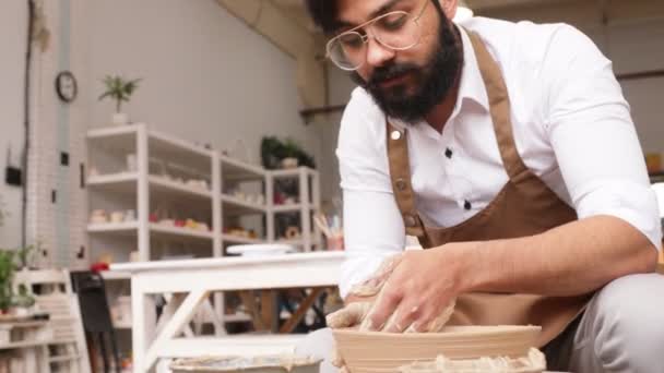 Creating vase of beige clay close-up. The sculptor in workshop makes jug out of clay closeup. Twisted potters wheel. Master crock. Potters work close-up. Man hands making clay jug. Handmade — Stockvideo