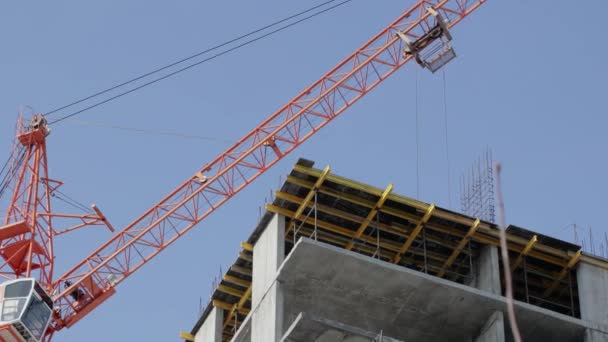 Las grúas de construcción mueven los materiales de construcción y trabajan en la construcción de edificios residenciales de varios pisos — Vídeo de stock