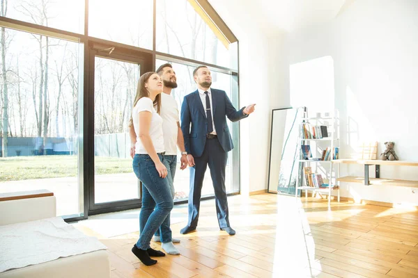 Agente de bienes raíces muestra a una pareja joven un nuevo hogar. familia compra vivienda — Foto de Stock