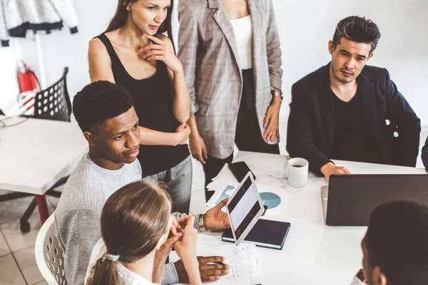 Un equipo de jóvenes trabajadores de oficina, empresarios con portátil trabajando en la mesa, comunicándose juntos en una oficina. Corporativosvapor y gerente en una reunión. coworking. — Foto de Stock