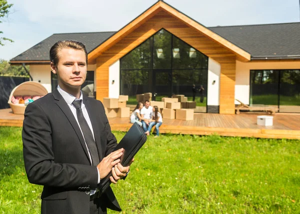 Ejendomsmægleren sælger en lejlighed til en ung familie. indgåelse af en leje og køb af et hus, lejlighed. mand viser boliger - Stock-foto