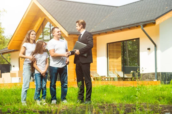 Agente inmobiliario está vendiendo un apartamento a una familia joven. la conclusión del arrendamiento y la compra de la casa, el apartamento. hombre muestra la vivienda — Foto de Stock