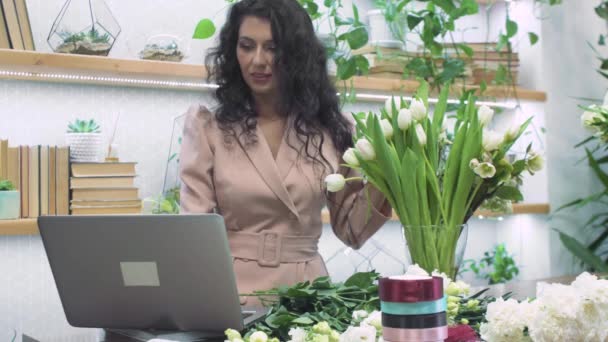 Genç çekici bayan çiçekçi işadamı çiçekçi dükkanında satılık bir buket çiçek yapıyor. İnsanlar, girişimcilik ve iş konsepti. — Stok video
