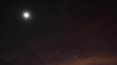 Zaman ayarlı gece videosu. Ay ve yıldızlar bulutların arasında hareket eder.