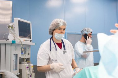 Bir grup doktor arasında bir anestezi uzmanının portresi enstrüman okumalarını ve hasta durumunu izliyor.