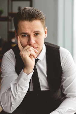 Ofiste takım elbiseli başarılı bir iş adamının portresi. Pencerenin yanındaki sandalyede otururken.