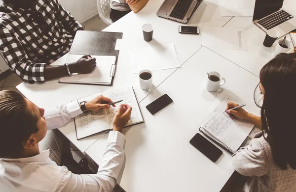 Vista superior del lugar de trabajo. Un equipo de jóvenes trabajadores de oficina, empresarios con portátil trabajando en la mesa, comunicándose juntos en una oficina. Corporativosvapor y gerente en una reunión. coworking . — Foto de Stock