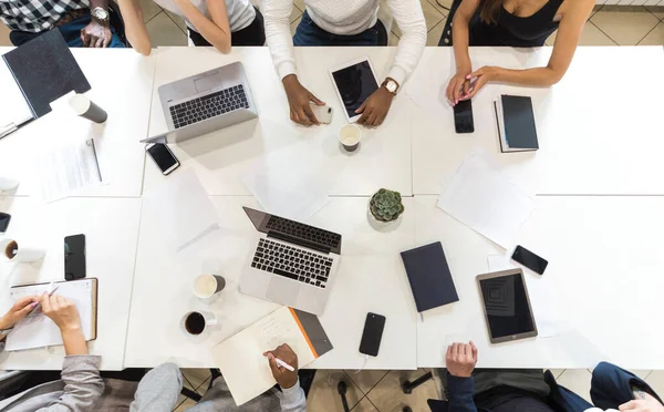 Vista superior del lugar de trabajo. Un equipo de jóvenes trabajadores de oficina, empresarios con portátil trabajando en la mesa, comunicándose juntos en una oficina. Corporativosvapor y gerente en una reunión. coworking . — Foto de Stock