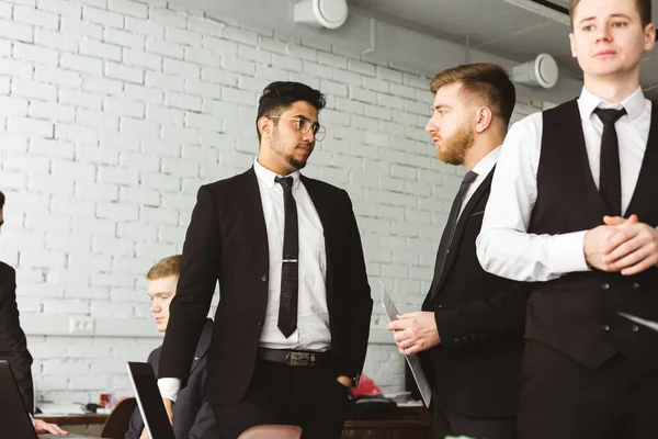 Diálogo de dos hombres en el trabajo, jóvenes empresarios en trajes trabajando y comunicándose juntos en una oficina. Corporativossteam y gerente en una reunión . — Foto de Stock