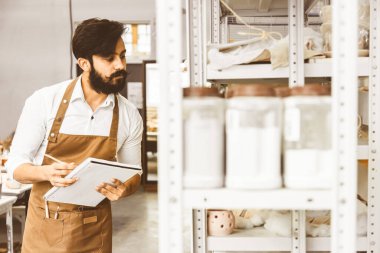 Genç ve çekici bir işadamı atölyesinde sakallı ve bıyıklı bir çömlekçi çalışıyor. Kayıtları ve kopyaları bir deftere kaydeder ürünlerle rafları inceler, bir envanter düzenler