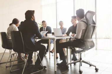 Masada oturan insanların siluetleri. Ofiste birlikte çalışan ve iletişim kuran genç iş adamlarından oluşan bir ekip. Şirket buharı ve bir toplantıda yönetici.