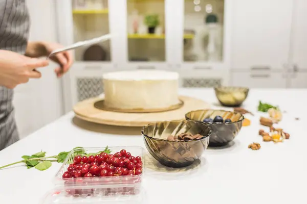 De banketbakker maakt witte room glad op een biscuittaart met een kookspatel. Het concept van zelfgemaakt gebak, het bakken van taarten. — Stockfoto