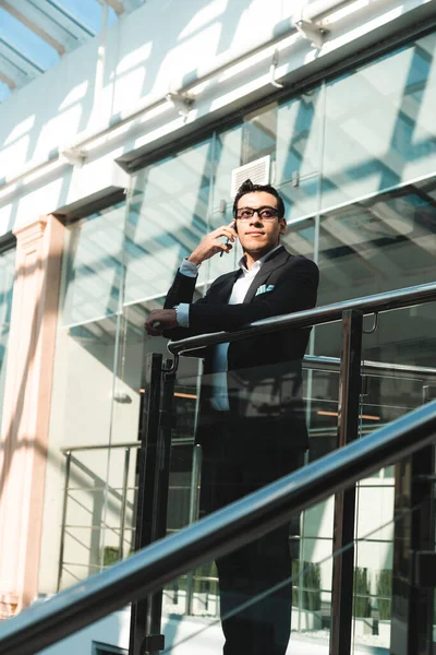 Retrato de un hombre de negocios en traje están de pie en el fondo de las oficinas de vidrio. — Foto de Stock