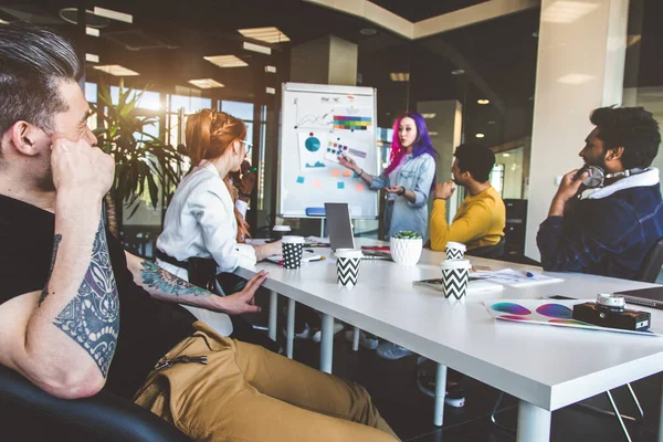 Grupo de ejecutivos multiétnicos discutiendo durante una reunión. Hombre y mujer de negocios sentados alrededor de la mesa en la oficina y sonriendo. Un equipo de jóvenes diseñadores creativos — Foto de Stock