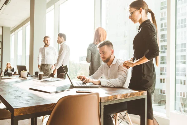 A team of young businessmen working and communicating together in an office. Corporate businessteam and manager in a meeting.