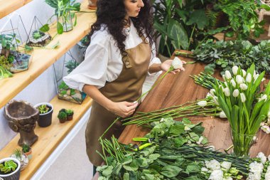 Çekici genç bayan çiçekçi bir çiçekçide çalışıyor..