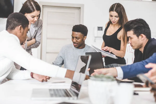 Un equipo de jóvenes trabajadores de oficina, empresarios con portátil trabajando en la mesa, comunicándose juntos en una oficina. Corporativosvapor y gerente en una reunión. coworking. — Foto de Stock