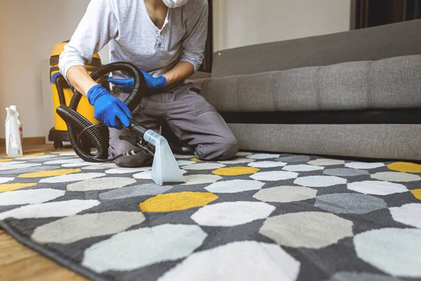 Stomerij man werknemer verwijderen van vuil uit tapijt, stofzuigen schoon met professionele apparatuur. — Stockfoto
