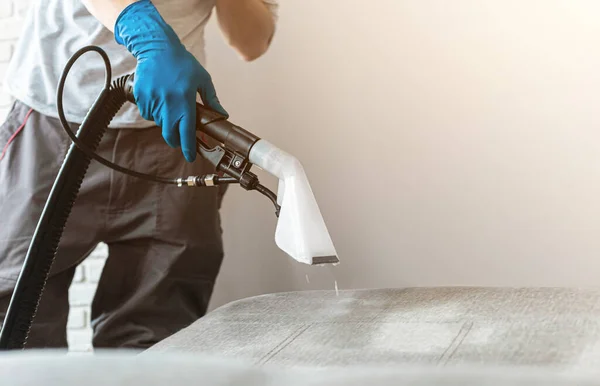 Hombre tintorerías empleado mano en guantes de goma protectora limpieza sofá con método de extracción profesional. Limpieza regular a principios de primavera. Concepto de empresa de limpieza comercial — Foto de Stock