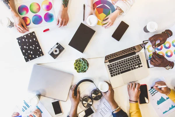 Grupo de ejecutivos multiétnicos discutiendo durante una reunión. Hombre y mujer de negocios sentados alrededor de la mesa en la oficina y sonriendo. Un equipo de jóvenes diseñadores creativos — Foto de Stock