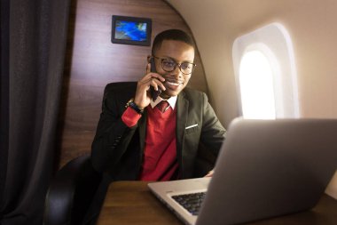 Onun özel jet sandalyede otururken gözlük bir dizüstü bilgisayar üzerinde çalışan çekici ve başarılı Afrikalı Amerikan işadamı
