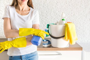 Profesyonel ev temizliği. Genç bir kadın daireyi temizliyor. Yakın plan, paçavra, sünger ve kova, malzeme personeli..