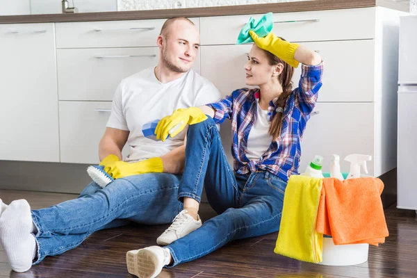 Young couple husband and wife do the house cleaning. The guy and the girl wash the kitchen with a mop and cloth, teamwork, fun — Stock Photo, Image