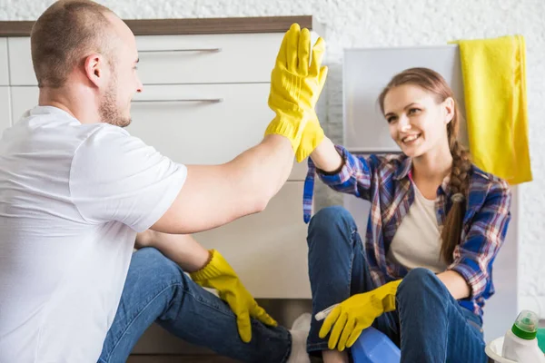 Ev temizliğini genç çift yapıyor. Erkek ve kız mutfağı paspas ve bezle yıkıyorlar. Takım çalışması, eğlence. — Stok fotoğraf