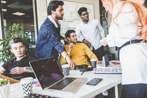 Grupo de ejecutivos multiétnicos discutiendo durante una reunión. Hombre y mujer de negocios sentados alrededor de la mesa en la oficina y sonriendo. Un equipo de jóvenes diseñadores creativos — Foto de Stock