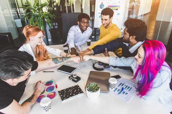 Grupo de ejecutivos multiétnicos discutiendo durante una reunión. Hombre y mujer de negocios sentados alrededor de la mesa en la oficina y sonriendo. Un equipo de jóvenes diseñadores creativos — Foto de Stock