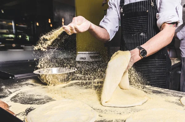 Professional chef cooking in the kitchen restaurant at the hotel, preparing dinner. A cook in an apron makes a salad of vegetables and pizza. — Stock Photo, Image