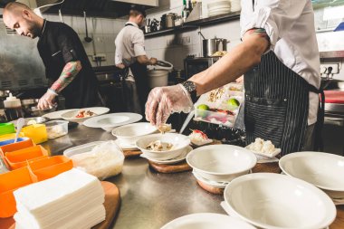 Oteldeki mutfak restoranında yemek pişiren profesyonel bir aşçı. Yemek hazırlıyor. Önlüklü bir aşçı sebze ve pizzadan salata yapar..