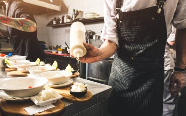 Oteldeki mutfak restoranında yemek pişiren profesyonel bir aşçı. Yemek hazırlıyor. Önlüklü bir aşçı sebze ve pizzadan salata yapar..