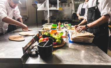 Oteldeki mutfak restoranında yemek pişiren profesyonel bir aşçı. Yemek hazırlıyor. Önlüklü bir aşçı sebze ve pizzadan salata yapar..