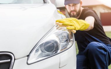 Temizlik servisi. Üniformalı ve sarı eldivenli bir adam araba yıkamada araba yıkar.