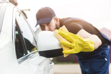 Temizlik servisi. Üniformalı ve sarı eldivenli bir adam araba yıkamada araba yıkar.