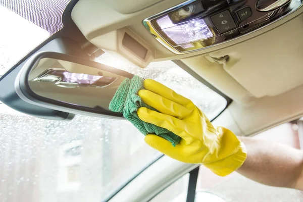 Cleaning service. Man in uniform and yellow gloves washes a car interior in a car wash