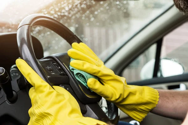 Städning. Man i uniform och gula handskar tvättar en bil interiör i en biltvätt — Stockfoto