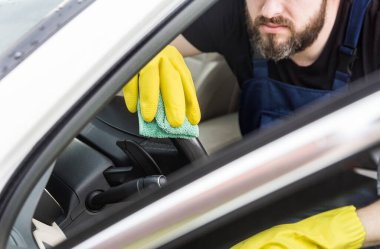 Temizlik servisi. Üniformalı ve sarı eldivenli bir adam araba yıkamada iç çamaşırlarını yıkıyor.