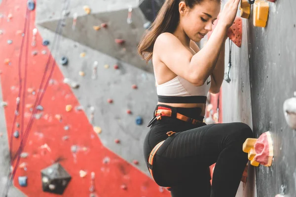 Sportnő mászó mozog fel a meredek sziklán, mászik a mesterséges falon beltérben. Extrém sport- és sziklaképződés — Stock Fotó