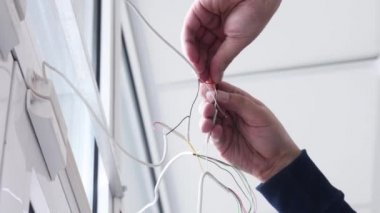 Elektrikçi konut elektrik tesisatının anahtar ve prizlerini bağlamak için kabloyu söküyor