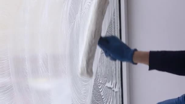 Ein professioneller Fensterputzer seift und drückt ein Fenster sauber, männliche Reinigungskraft. — Stockvideo