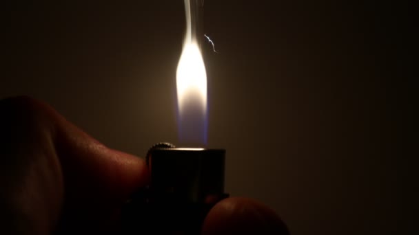 Hand with a lighter closeup. The moment of ignition. Sparks and flame on a dark background — Stock Video